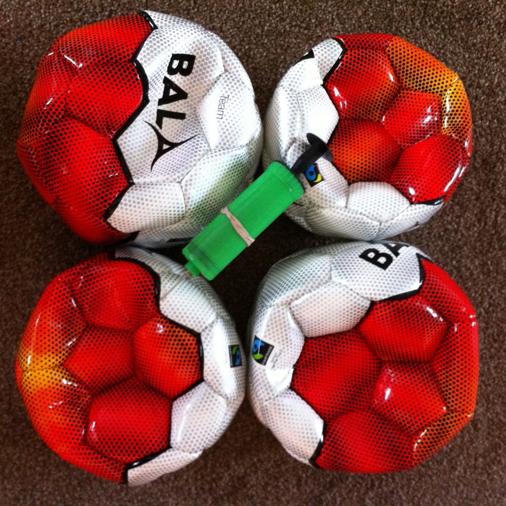 Photo of 3 footballs and a football pump